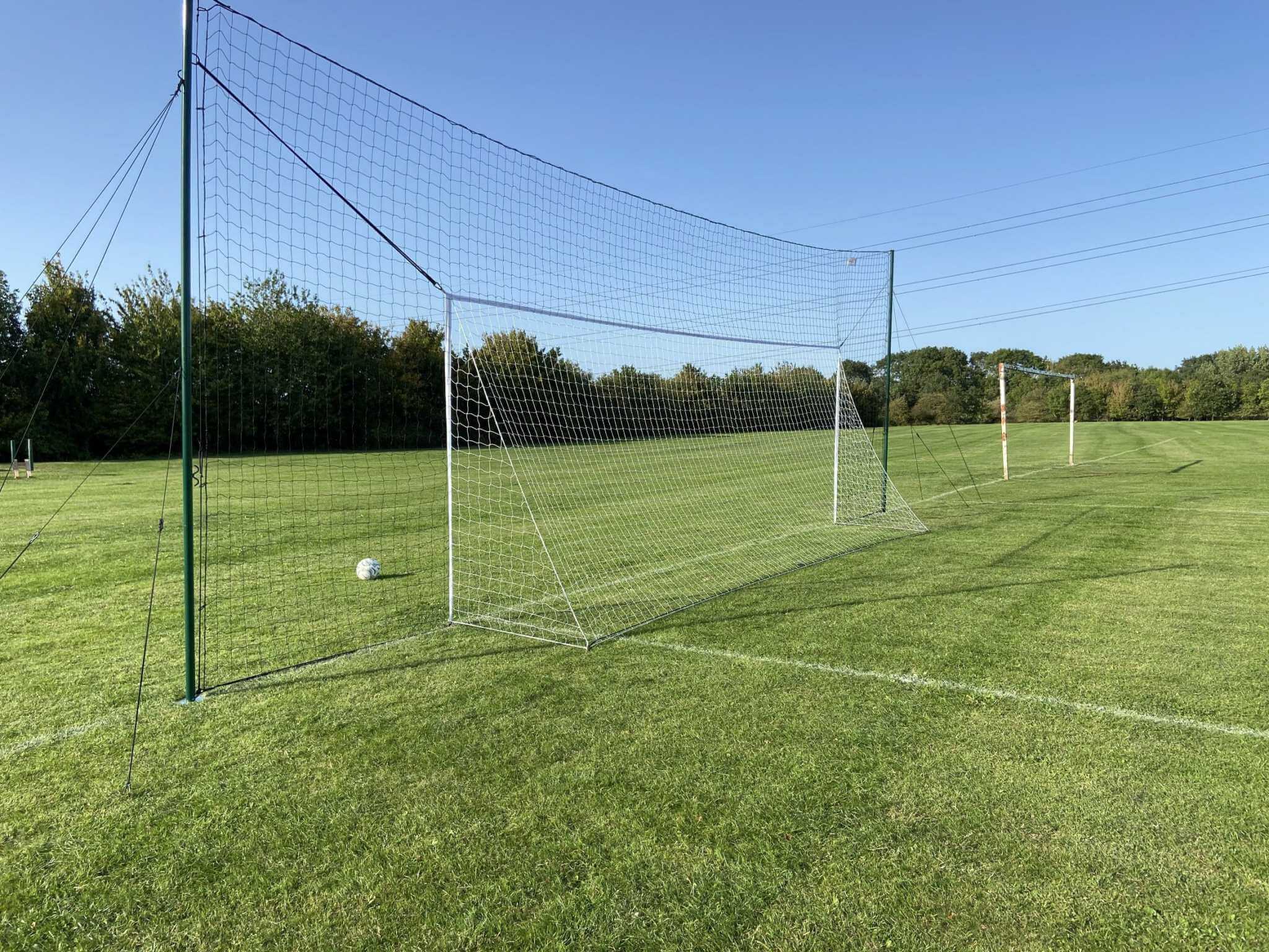 Missed shot bouncing off backstop net behind full size football goal