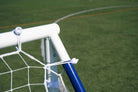 Close-up of a football rebounder goal trainer frame on a grassy field, showcasing its sturdy design and net attachment.