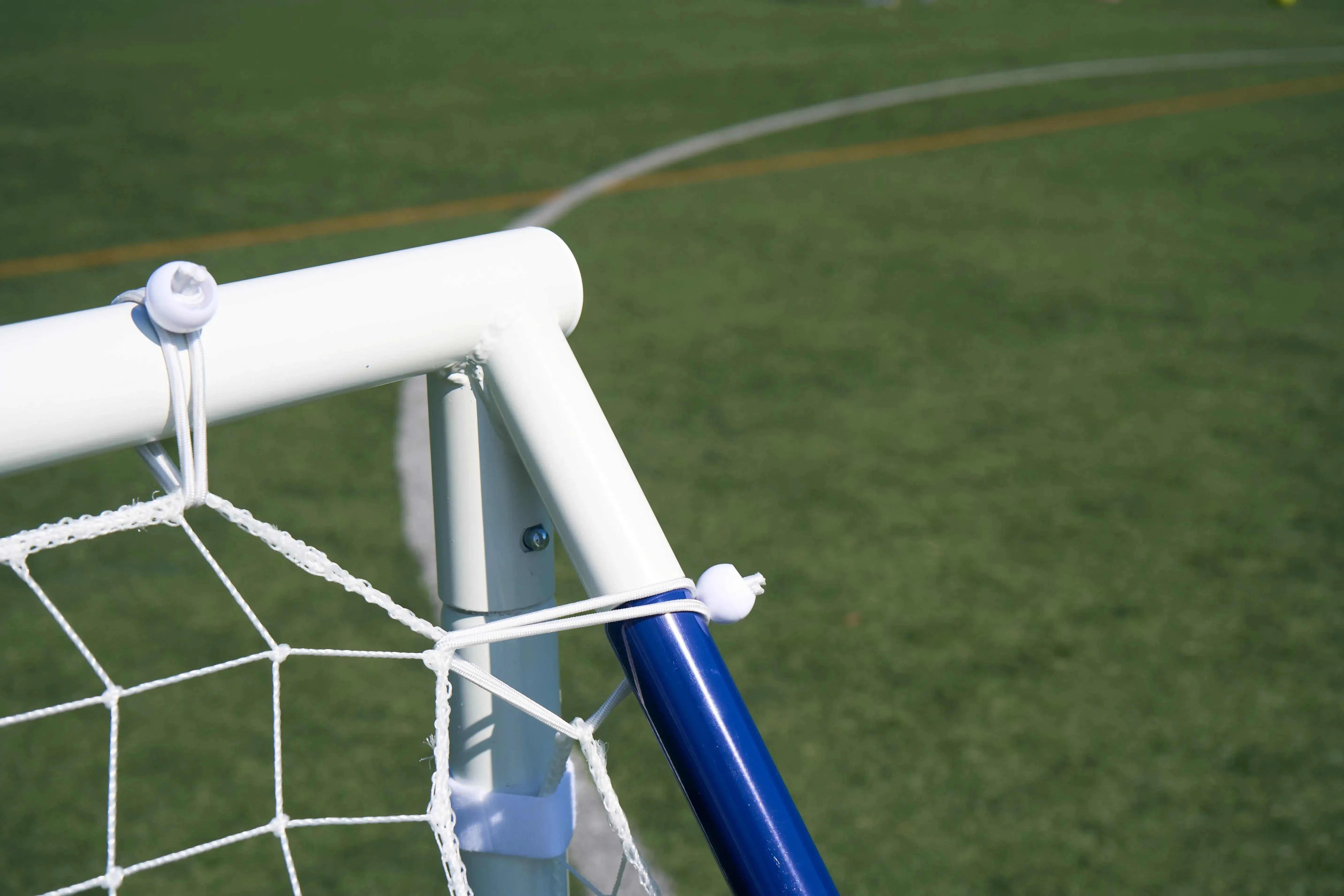 Close-up of a football rebounder goal trainer frame on a grassy field, showcasing its sturdy design and net attachment.