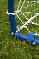 Close-up of the durable metal frame and net attachment of a football rebounder goal trainer on grass.